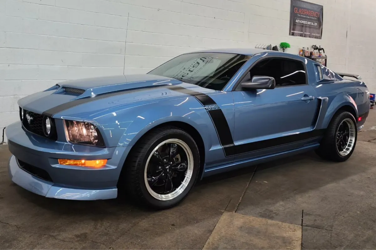 Blue Ford Mustang with black stripes inside detailing shop