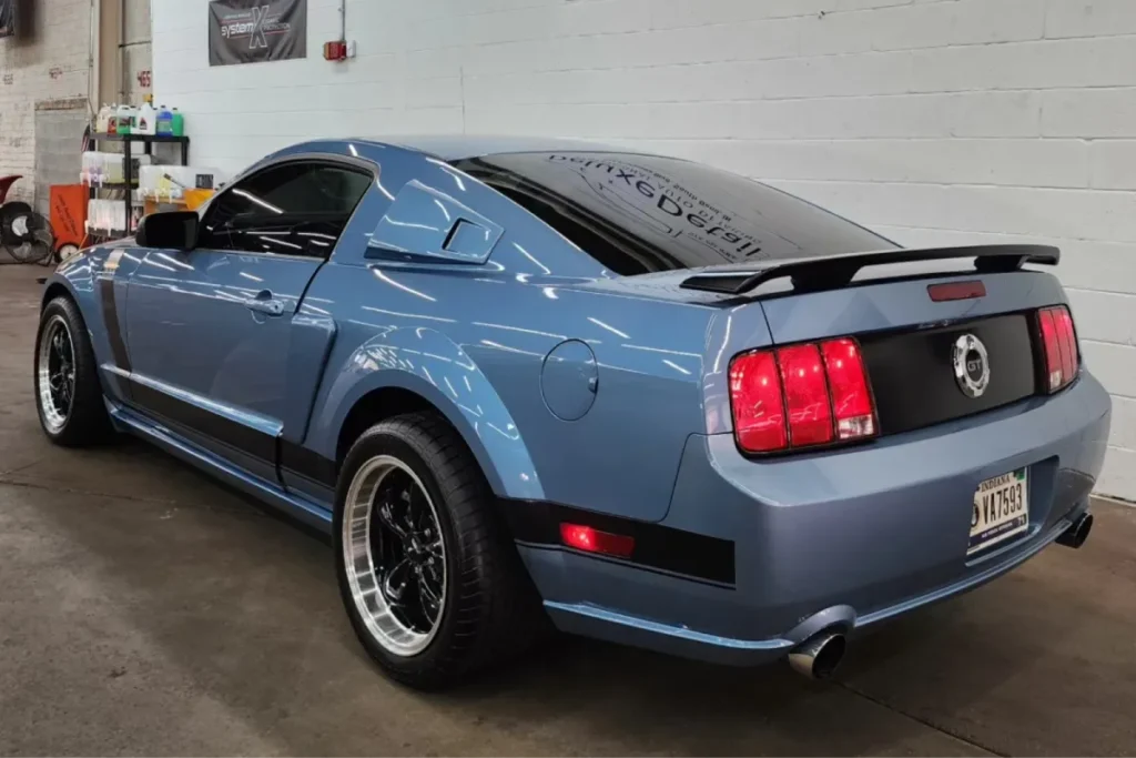 Classic blue Mustang with glossy finish and black accents in garage