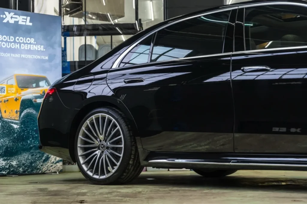 Black Mercedes-Benz sedan with a glossy finish and XPEL advertisement in the background