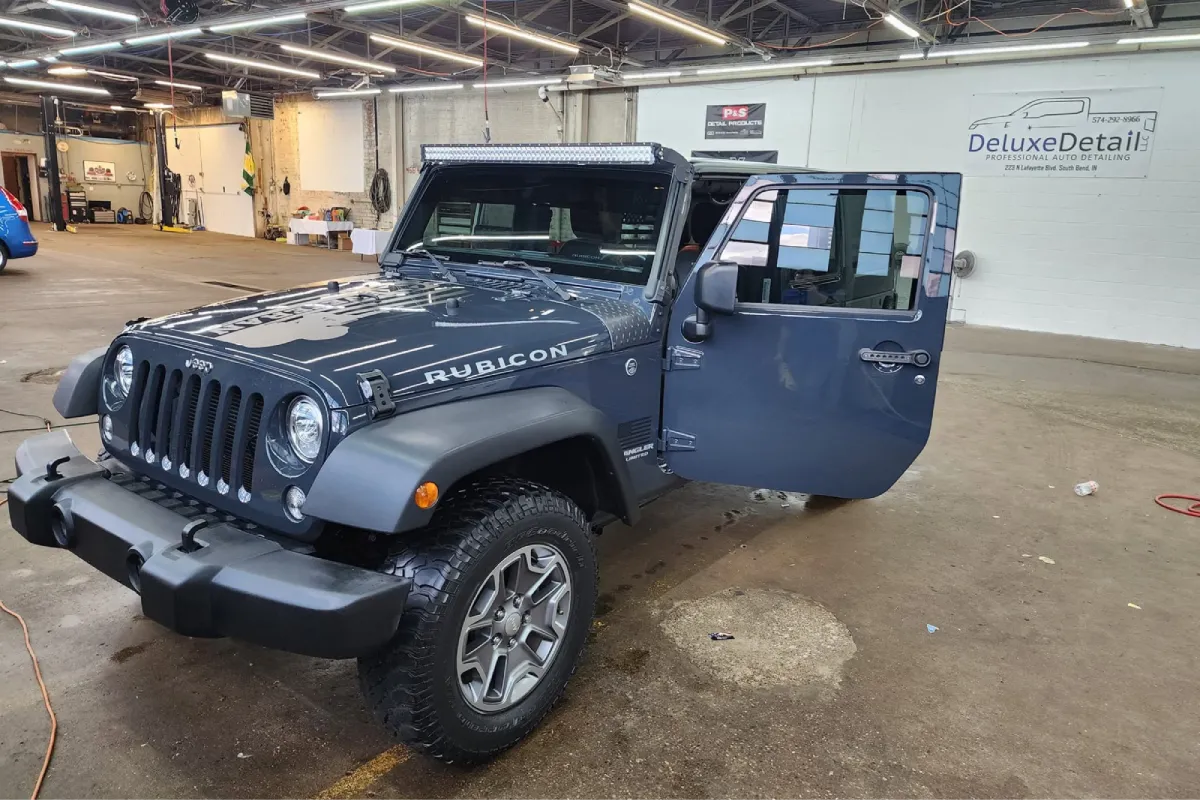 Jeep Wrangler with dark window tint inside an auto detailing shop.