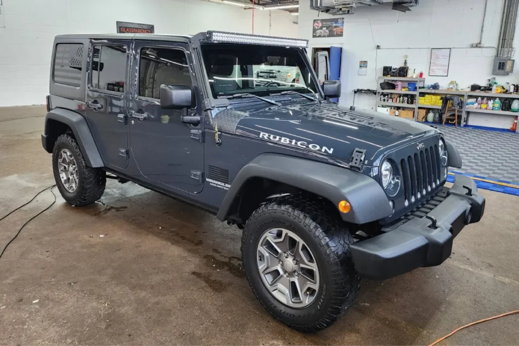 Jeep Wrangler with newly tinted windows in a professional detailing garage.