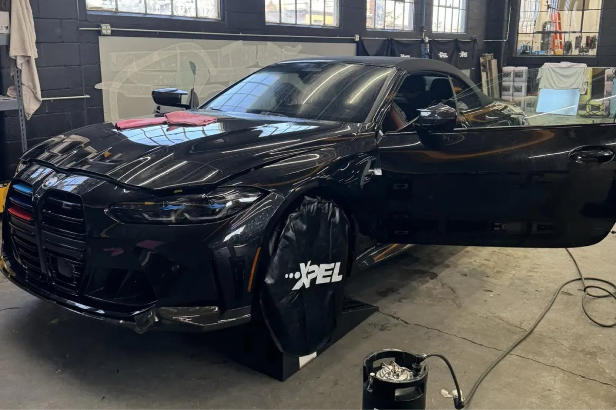 Black BMW with paint protection film installation in progress.